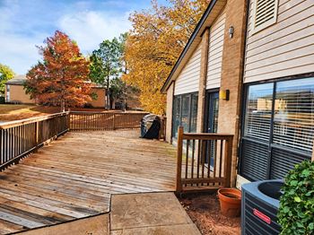 A deck with a railing and a tree in the background.